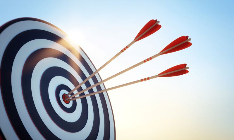 Three arrows with red feathers have struck the bullseye of a black-and-white target. © By peterschreiber.media/stock.adobe.com